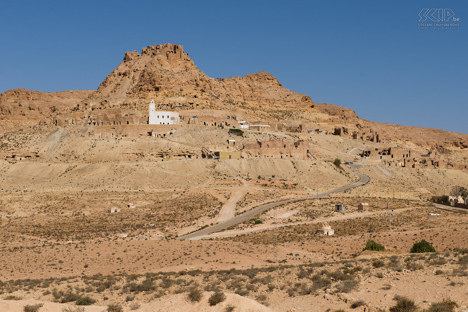Douiret Het verlaten Berber dorp Douiret, schitterend tegen de heuvel aangebouwd, was ooit een stopplaats op de karavaanroute van Ghabès naar Ghadamis. Het dorpje van Douriret is van onderaan de heuvel amper zichtbaar en gaat volledig op in het landschap van de honderd meters lange berg. De meest indrukwekkende huizen van Douiret zijn al lang verlaten. Sommige van de huizen zijn 3 tot 4 verdiepingen hoog. Sommige kamers hebben muurschilderingen en gravures in de plafonds. Rond 1850 woonden er ongeveer 3500 mensen. Nu zijn er nog 5 families die er de traditie verder zetten. De belangrijkste inkomstenbron van Douiret kwam van olijven waaruit olie werd gewonnen door molens die door kamelen werden bewogen. Stefan Cruysberghs